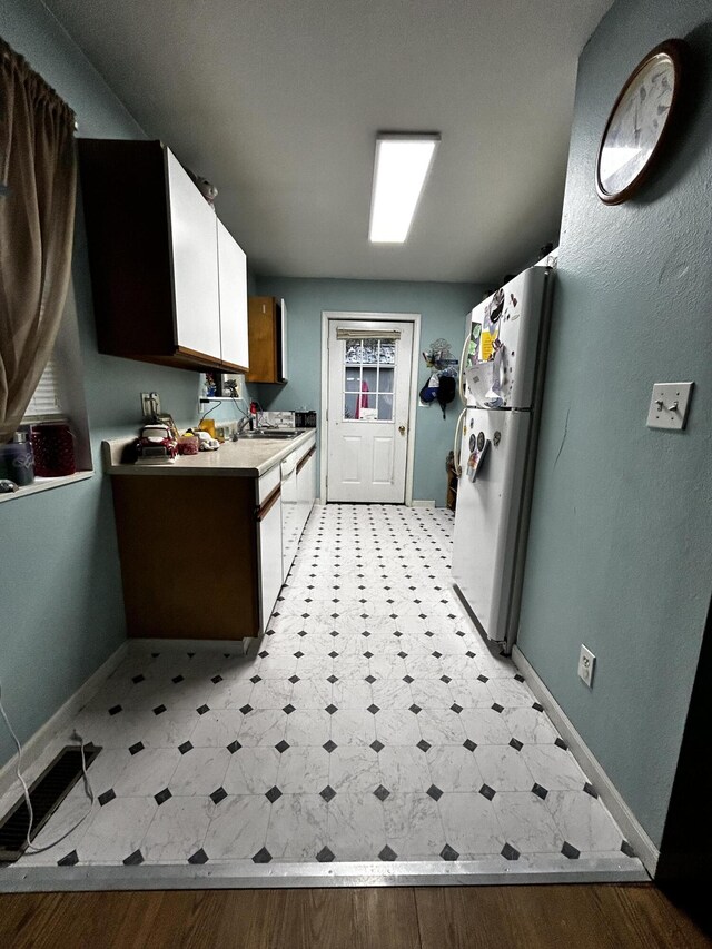 3714 W Hastings Lake Rd, Jonesville, MI 49250 - kitchen with freestanding refrigerator, light floors, baseboards, light countertops, and white cabinetry