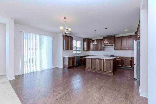 kitchen featuring dark wood-type flooring, a kitchen island, pendant lighting, and appliances with stainless steel finishes