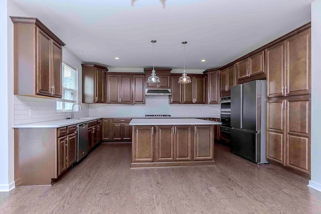 kitchen with a center island, hanging light fixtures, tasteful backsplash, wood-type flooring, and stainless steel appliances