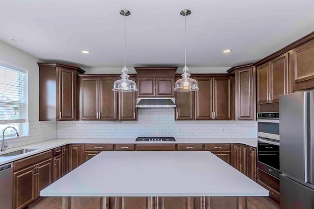 kitchen featuring sink, a center island, backsplash, pendant lighting, and appliances with stainless steel finishes