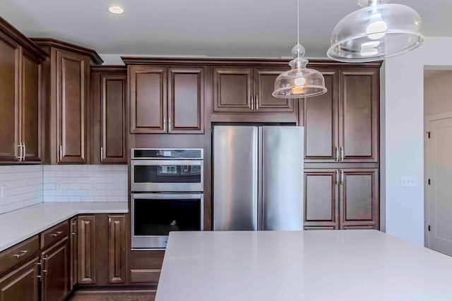 kitchen with dark brown cabinetry, stainless steel appliances, hanging light fixtures, and tasteful backsplash