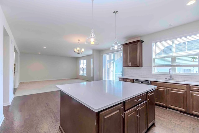 kitchen featuring dark brown cabinetry, sink, tasteful backsplash, a kitchen island, and hardwood / wood-style flooring