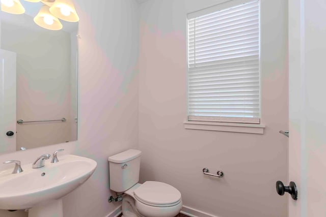 bathroom featuring toilet, a healthy amount of sunlight, and sink