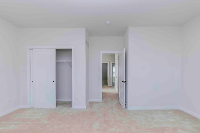 unfurnished bedroom with light carpet and a closet