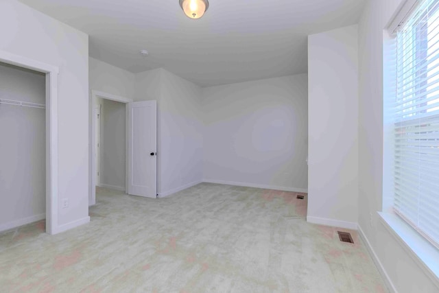 unfurnished bedroom with a closet and light colored carpet