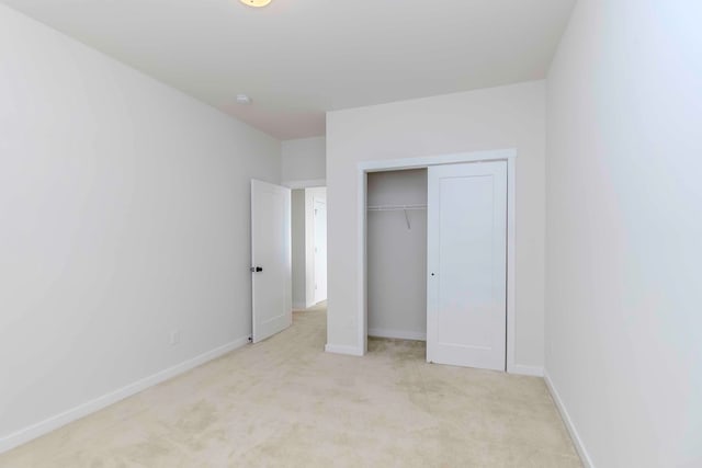 unfurnished bedroom featuring light colored carpet and a closet