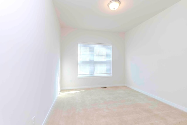 carpeted spare room featuring lofted ceiling