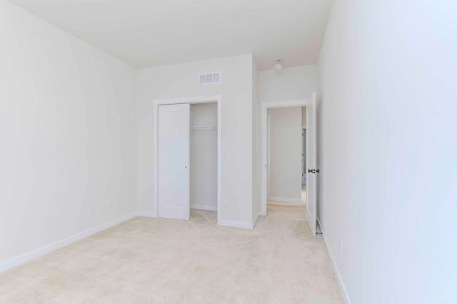 unfurnished bedroom with light carpet and a closet