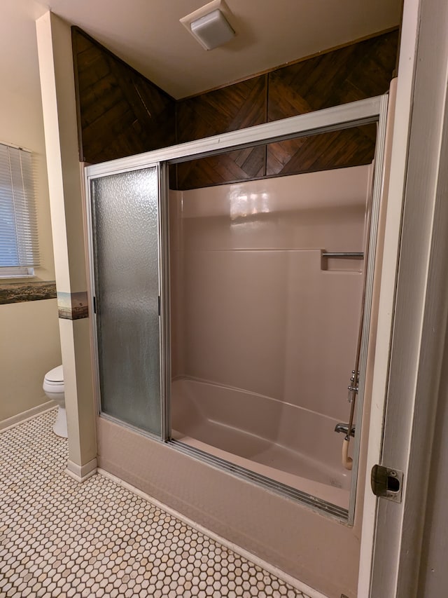 bathroom with combined bath / shower with glass door, tile patterned flooring, and toilet