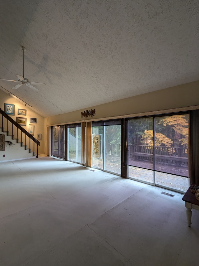 unfurnished living room featuring a textured ceiling, ceiling fan, concrete flooring, and lofted ceiling