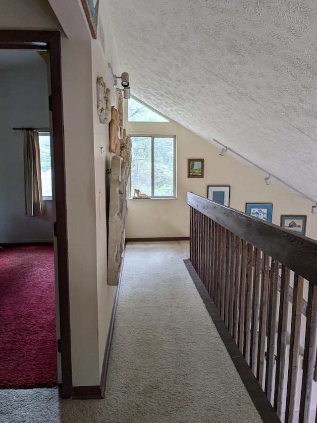 hallway with carpet, a textured ceiling, and vaulted ceiling