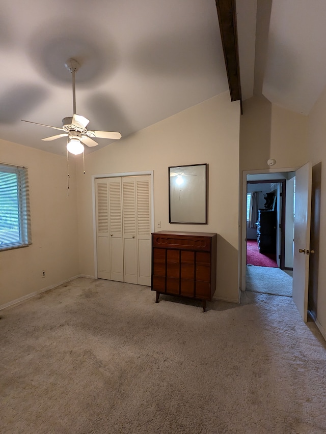 unfurnished bedroom with ceiling fan, lofted ceiling with beams, light carpet, and a closet