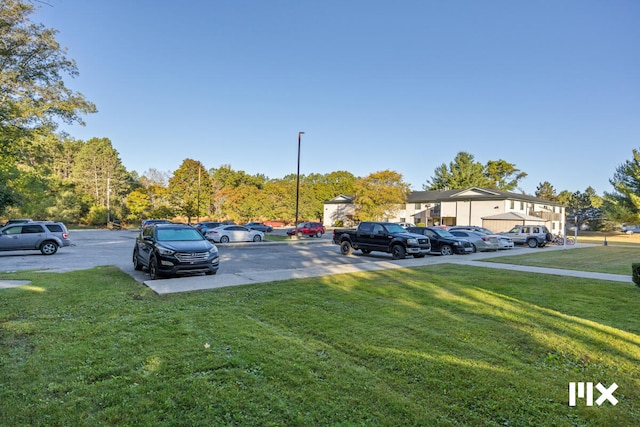 view of parking / parking lot featuring a lawn