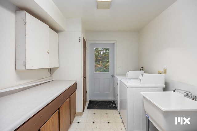 clothes washing area featuring washer and clothes dryer, cabinets, and sink