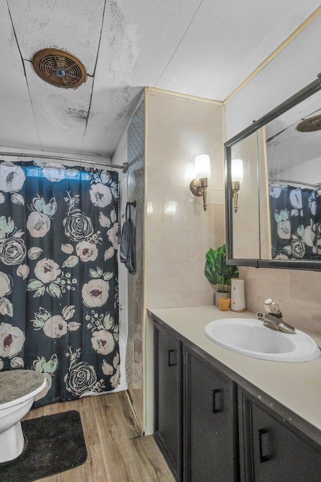 full bathroom with hardwood / wood-style floors, vanity, tile walls, and shower / bath combo with shower curtain