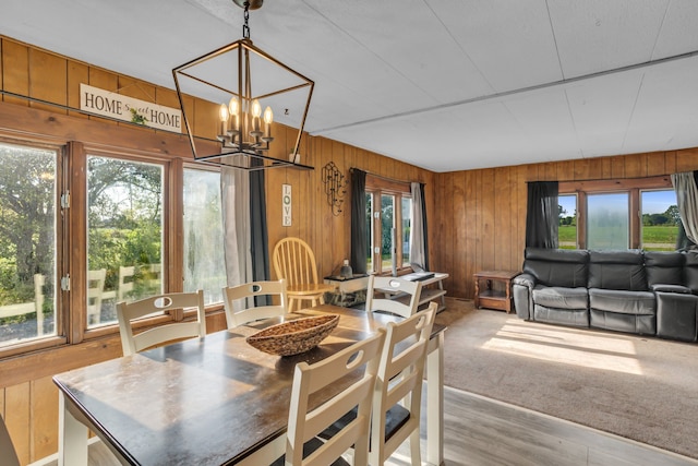 dining space featuring a notable chandelier, light hardwood / wood-style floors, and wooden walls