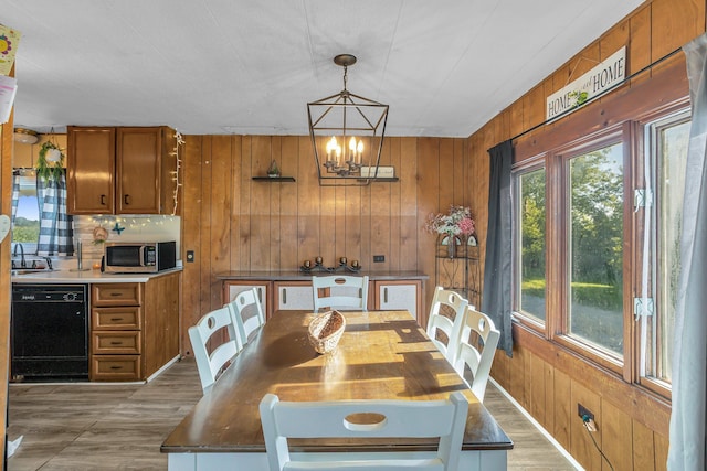 dining area featuring hardwood / wood-style floors, wood walls, sink, and a chandelier