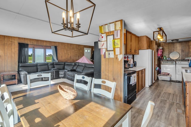 dining room with independent washer and dryer, dark hardwood / wood-style flooring, an inviting chandelier, and wooden walls