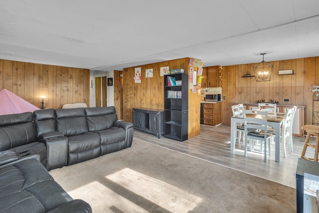 living room with wood walls, a notable chandelier, and light wood-type flooring