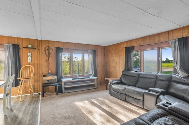 living room with beam ceiling, a wealth of natural light, wooden walls, and carpet floors