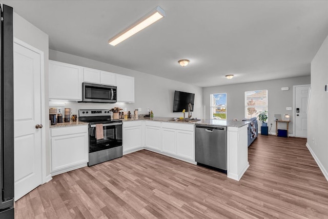 kitchen with kitchen peninsula, light hardwood / wood-style flooring, white cabinets, and appliances with stainless steel finishes