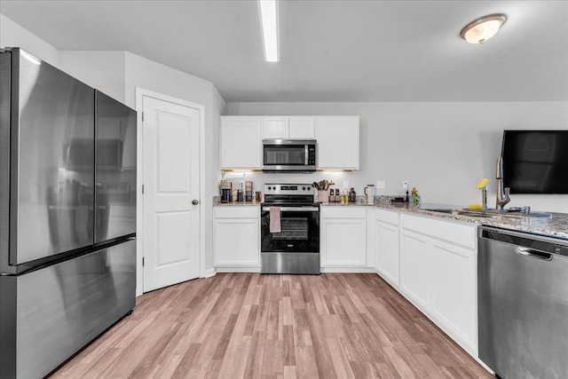 kitchen with light hardwood / wood-style floors, white cabinetry, sink, and appliances with stainless steel finishes