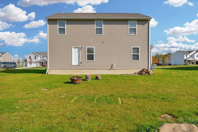 back of property featuring an outdoor fire pit and a lawn