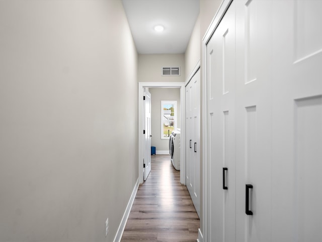 hallway with light hardwood / wood-style flooring and washer / dryer