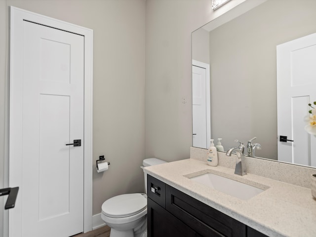 bathroom with hardwood / wood-style flooring, vanity, and toilet