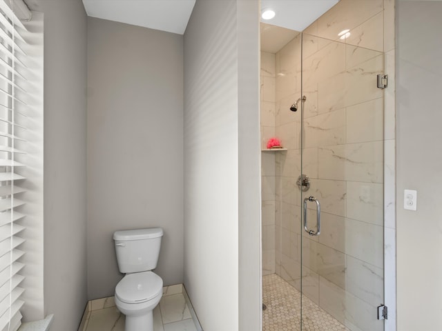 bathroom featuring tile patterned flooring, toilet, and a shower with shower door