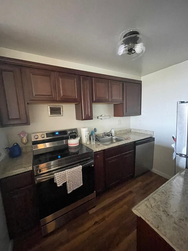 kitchen featuring dark brown cabinets, dark hardwood / wood-style flooring, sink, and appliances with stainless steel finishes