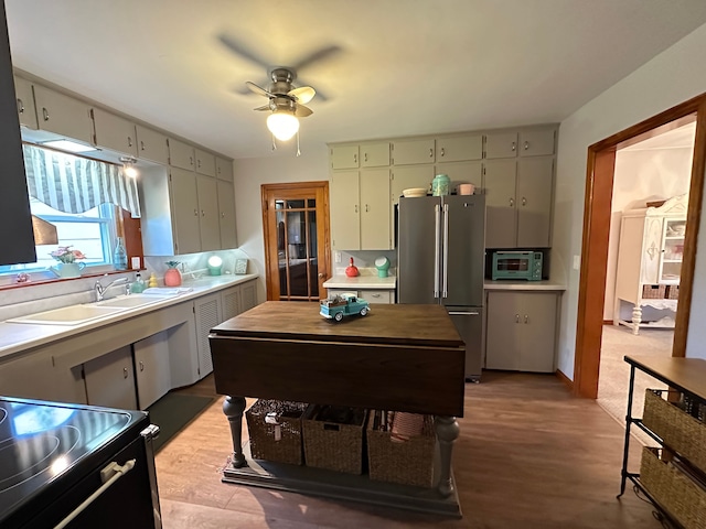 kitchen with sink, ceiling fan, a center island, high end refrigerator, and light wood-type flooring