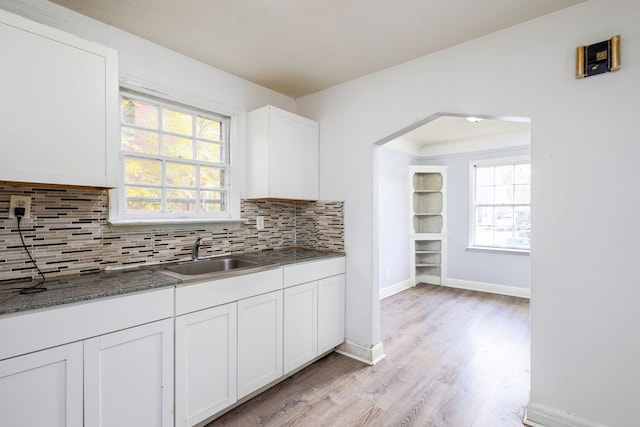 kitchen featuring decorative backsplash, a wealth of natural light, sink, light hardwood / wood-style flooring, and white cabinetry