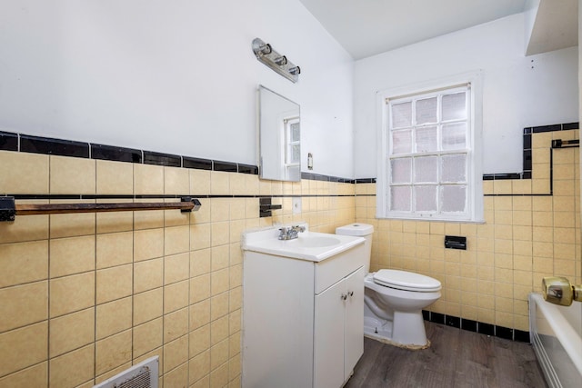 bathroom featuring vanity, toilet, tile walls, wood-type flooring, and a tub