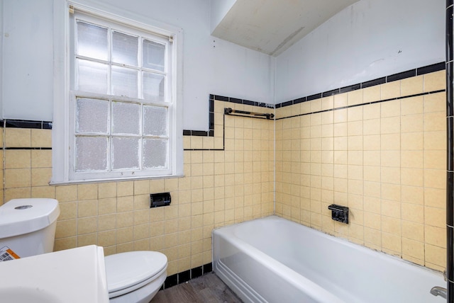 bathroom featuring a bathing tub, toilet, wood-type flooring, and tile walls