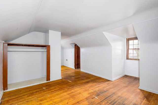 additional living space with hardwood / wood-style floors and lofted ceiling