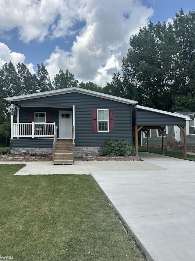 manufactured / mobile home featuring a carport, a porch, and a front lawn