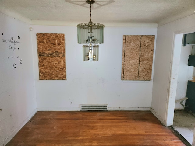 unfurnished dining area featuring hardwood / wood-style floors and a textured ceiling