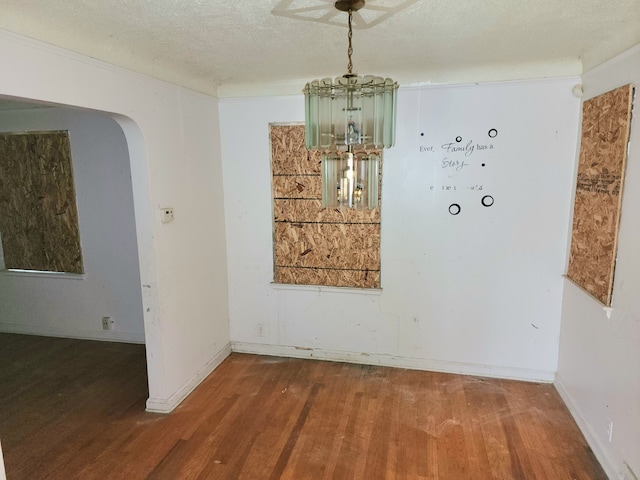 unfurnished dining area with wood-type flooring and a textured ceiling