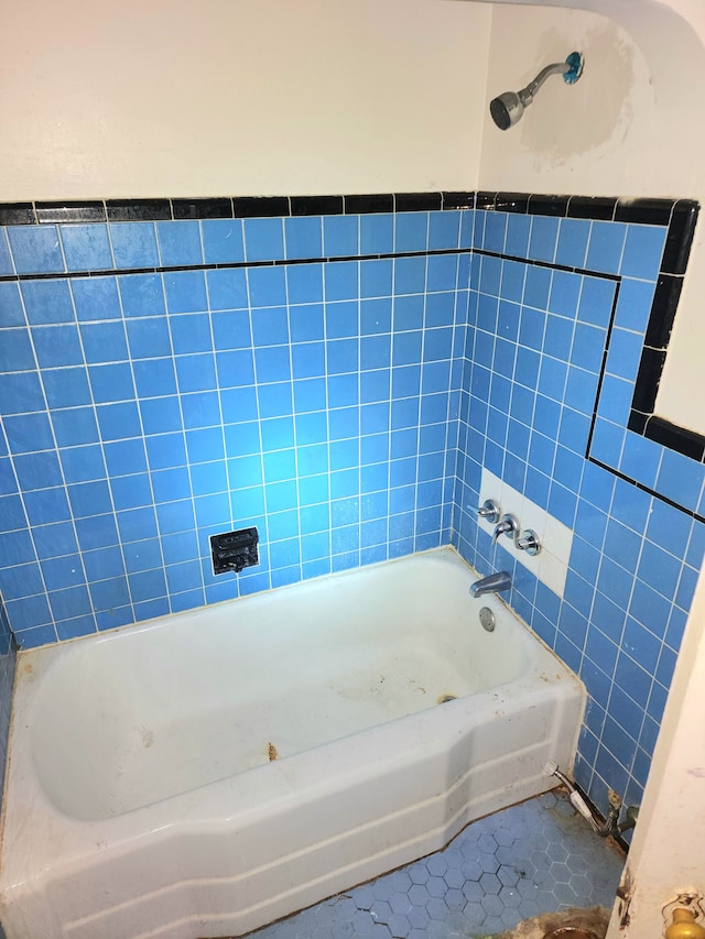 bathroom with tile patterned floors, a tub to relax in, and tile walls