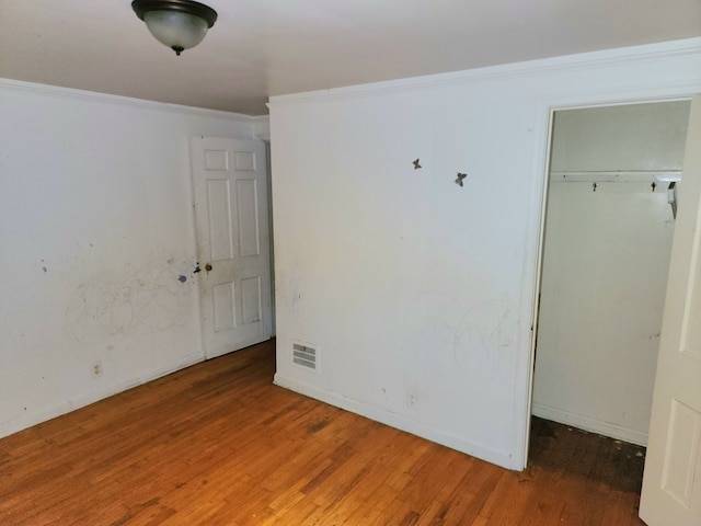 unfurnished bedroom featuring a closet, hardwood / wood-style floors, and ornamental molding