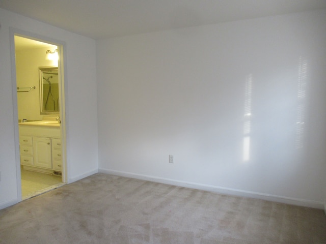 unfurnished bedroom with connected bathroom, light carpet, and sink