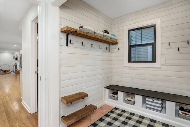 mudroom with wood walls and light hardwood / wood-style flooring