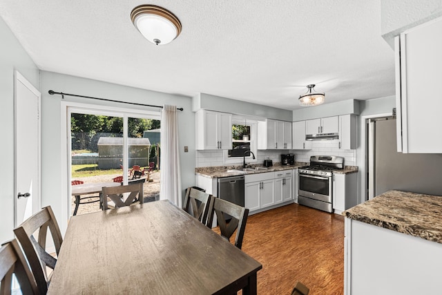 kitchen featuring sink, dark stone countertops, stainless steel appliances, decorative backsplash, and white cabinets