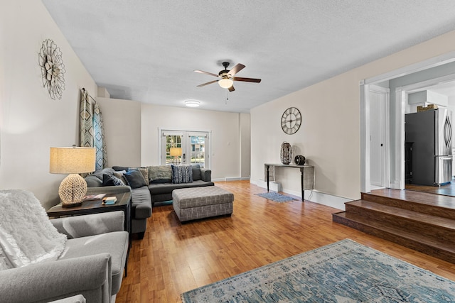 living room with ceiling fan, hardwood / wood-style floors, a textured ceiling, and french doors