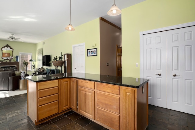 kitchen with ceiling fan, dark stone countertops, and hanging light fixtures