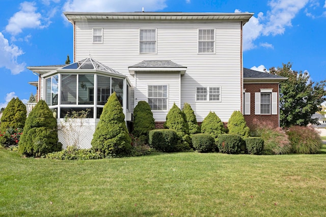 rear view of house featuring a lawn and a sunroom