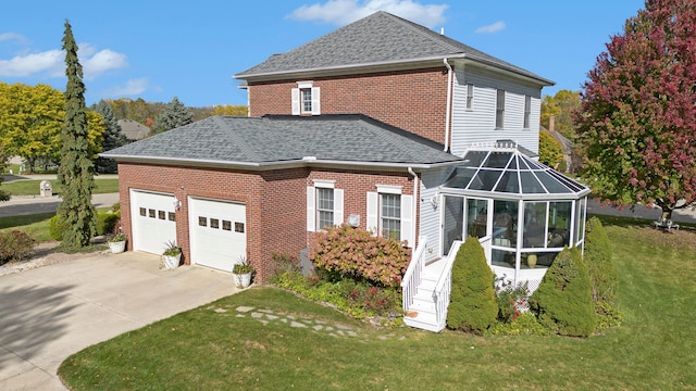 exterior space with a garage, a lawn, and a sunroom