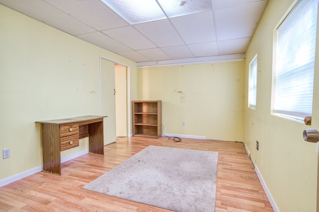 spare room featuring a paneled ceiling and light hardwood / wood-style flooring