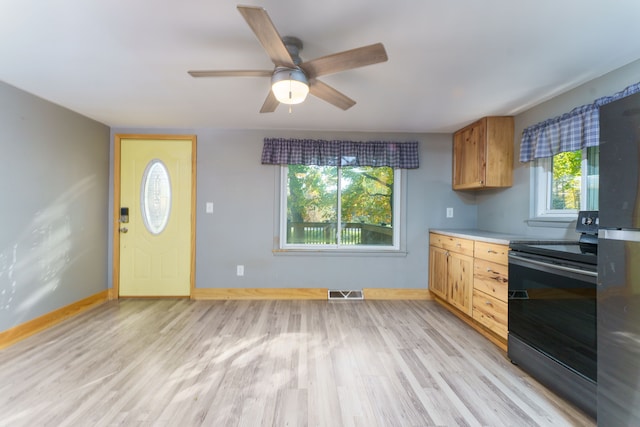 kitchen featuring ceiling fan, black electric range oven, a healthy amount of sunlight, and light hardwood / wood-style floors